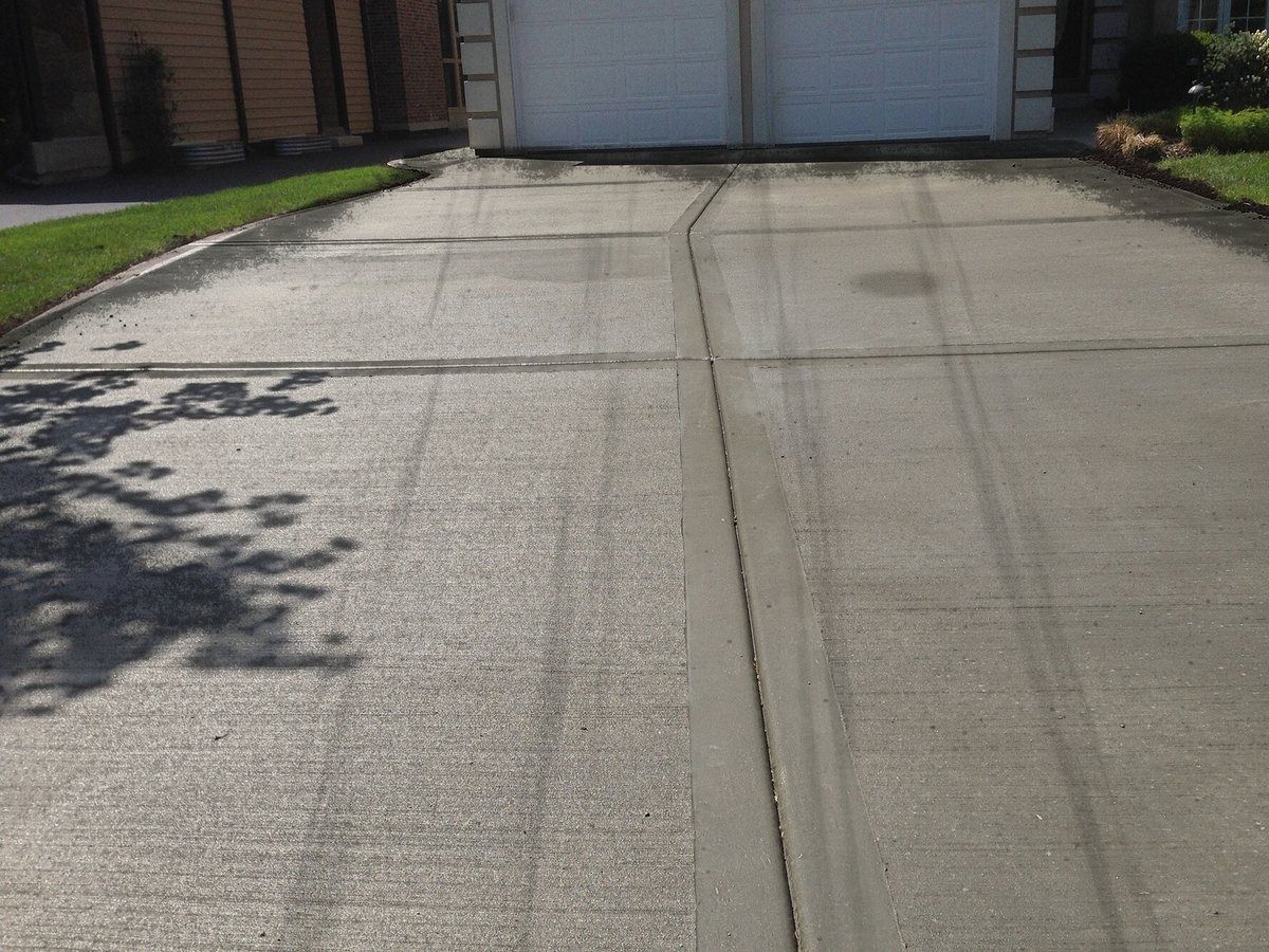Close-up of concrete driveway before cleaning with mould in the joints, a drip stain and tyre marks